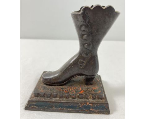 A vintage cast metal figure of a Victorian boot screwed onto a stepped base with remnants of original paintwork. Approx. 13cm