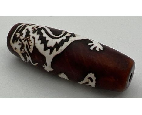 A ceramic Tibetan dzi bead with inlaid dragon detail. Approx. 4cm long. 