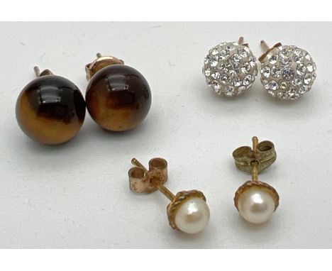 3 pairs of 9ct gold and yellow metal stud style earrings. Tigers eye, crystal studded balls and small white pearl set studs. 