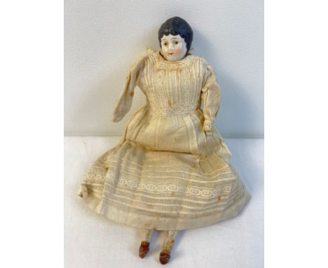 An antique 9.5" porcelain doll with straw filled body in Edwardian dress. Porcelain head, hands and feet with hand painted fa