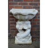 A white painted classical style water feature, the shell shaped top supported by a pair of