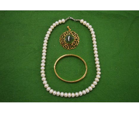 A gilt metal bangle, pearl necklace and a gilt metal pendant.