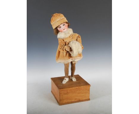 A late 19th/ early 20th century French bisque head doll automaton, modelled with a young girl wearing winter clothing of velv