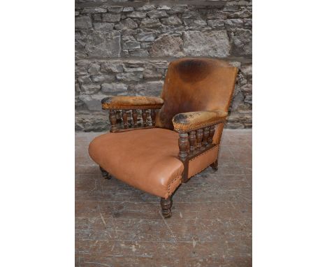 A Victorian oak armchair, with leather upholstered back and arms supported on baluster turned spindles, above a later leather