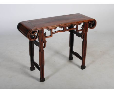 A Chinese dark wood altar table, late 19th/ early 20th century, the panelled rectangular top pierced and scroll carved frieze