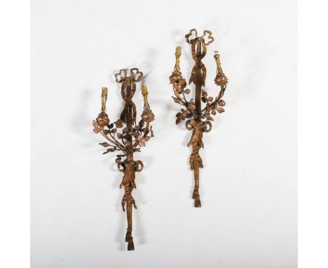 A pair of gilt metal two light wall sconces, the foliate cast nozzles supported on flowering branch arms suspended by ribbon 
