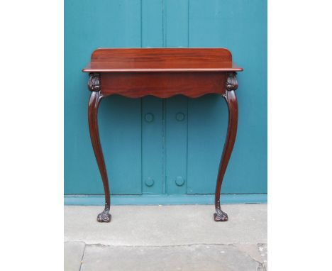 A 19th century and later mahogany console table, the later top above a shaped frieze, raised on four scroll carved cabriole s