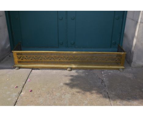 A 19th century brass fender, with pierced details, raised on five paw feet, 147cm wide x 36cm deep.