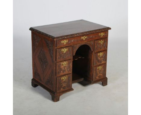 A 19th century oak knee hole desk, the rectangular top with a foliate carved edge, above a long frieze drawer and knee hole, 