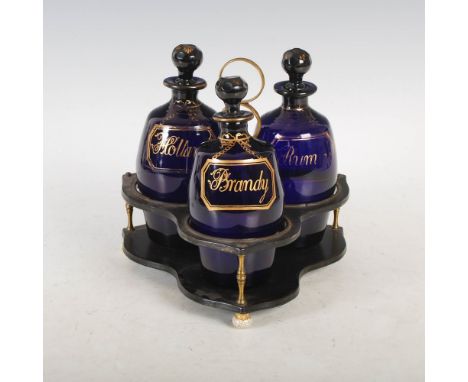 An early 19th century three bottle Bristol Blue glass decanter set, comprising three swollen cylindrical decanters with facet