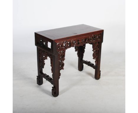 A Chinese dark wood altar table, Qing Dynasty, the panelled rectangular top above relief carved, pierced and scrolling geomet