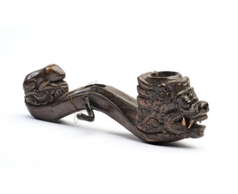 A CARVED WOOD PULLEY, BALI, INDONESIA, 19TH CENTURY in the form of a leonine naga with serpentine body, the wheel with handle