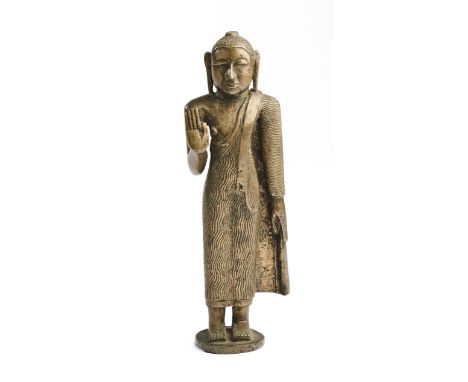 A SINHALESE BRONZE STANDING FIGURE OF BUDDHA, SRI LANKA, 19TH CENTURY standing with right hand raised in abhaya mudra, wearin