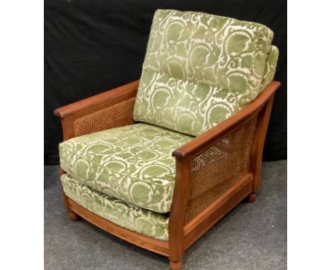 An Ercol golden oak bergere armchair, green and cream cushioned back and seat 