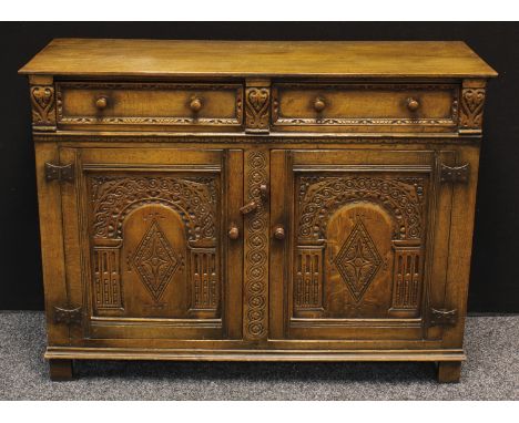 A 20th century oak kitchen sideboard, slightly over sailing rectangular top above a pair of short drawers and a pair of carve