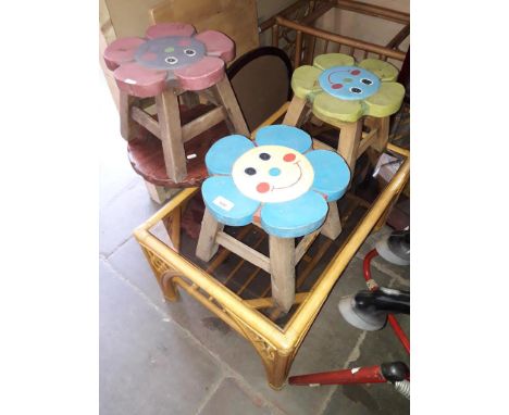 Three children's stools, a wooden tripod table and a cane and glass table. 