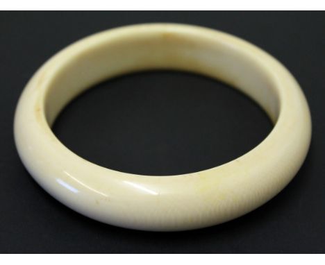 An ivory bangle, early 20th Century. Diam. 10cm. Condition - good, general wear to include minor hairlines, no chips.