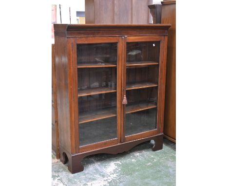 A Victorian mahogany bookcase, stepped cornice, two glazed doors enclosing adjustable shelving, later base, shaped apron, sha