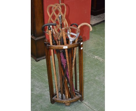 A 1940's corner stick stand; a white metal mounted parasol; other parasols; various walking sticks and canes; a carpet beater