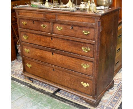 A George III oak chest, oversailing top above a deep frieze with two secret drawers, two short over three long graduated cock