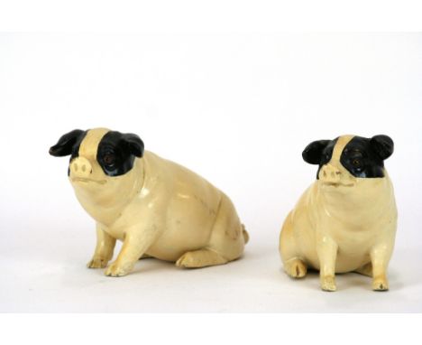 A pair of pottery model pigs with glass eyes, 14.5cm high
