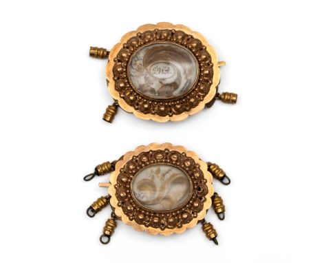 Twee 14 kt. gouden sluitingen met haarwerk, 19e eeuw. Beide met een decor van krullen, en geschulpte zetrand met decor van bo