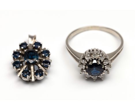 14 kt. Witgouden ring, centraal bezet met een ronde gefacetteerde donkerblauwe saffier (diam. ca. 5,80 mm) in een entourage v