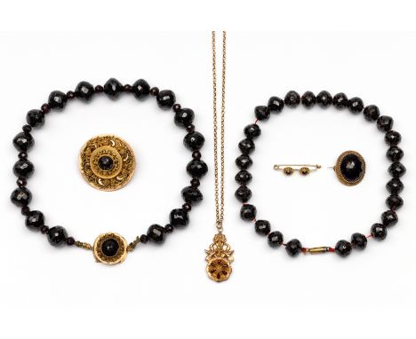 Een collectie sieraden met granaat Een 18 kt. gouden ronde filigrain broche, 19e eeuw en twee colliers met granaten kralen, w