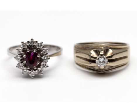 Twee witgouden ringen. Eén in 14 kt. goud, centraal bezet met ovale gefacetteerde robijn (ca. 6,2 x 4,6 mm) in een entourage 