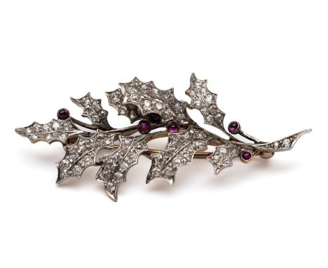 18 kt. Geel- met witgouden broche, in de vorm van een tak hulst.  De bladeren bezet met oud briljant geslepen diamant, de bes