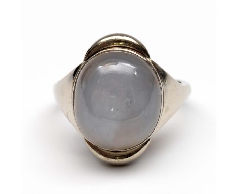 14 kt. Witgouden ring, bezet met een ovale licht blauw grijze stersaffier (h. 14 x b 12,5 mm bruto 7,9 gr., ringmt. 16,25 [1]