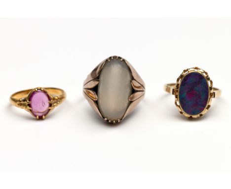 Drie gouden ringen. Een 14 kt. gouden ring bezet met opaal doublet, één beneden wettelijk gehalte gouden ring bezet met paste