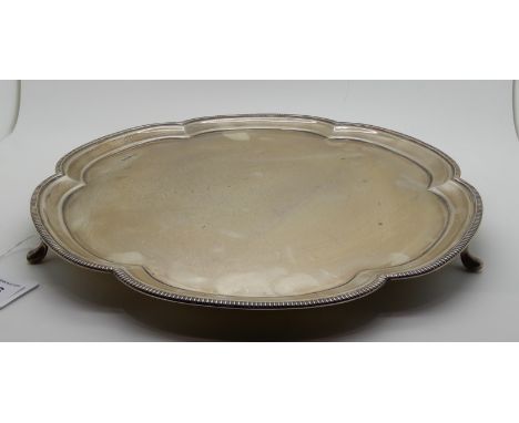 A silver salver by James Dixon &amp; Son, Sheffield 1939 of scalloped circular form with gadrooned rim on three pad feet, 31c