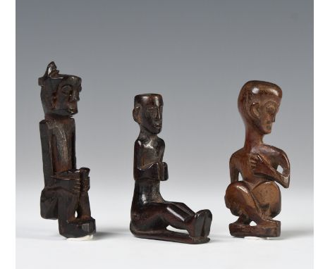 Borneo, East-Kalimantan, three wooden amulets, one showing a cross-legged seated figure, the head turned to the left, a Benua