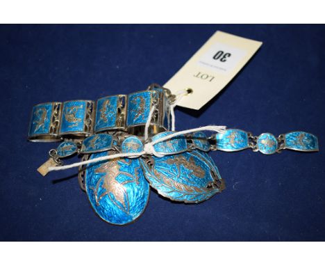 A silver and blue enamel suite of matching Siamese jewellery, to include: two brooches; a pendant; and two bracelets, decorat