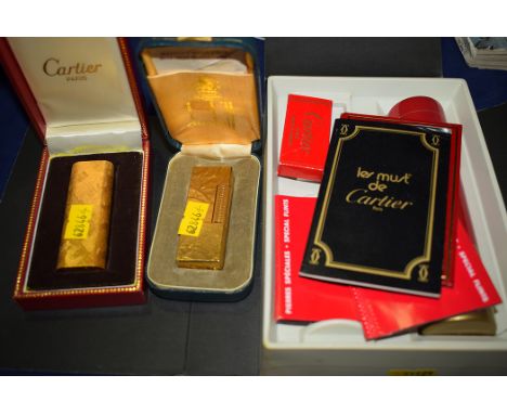 A Cartier gold-plated lighter; and a Dunhill gold-plated lighter; together with a Cartier gas refill tank.