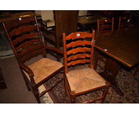 A set of reproduction stained wood ladder back dining chairs, four singles and two carvers, rush seats.