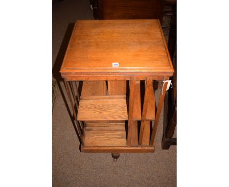 An early 20th Century oak revolving bookcase, terminating in brass castors (one ceramic)., 81.5cms high.