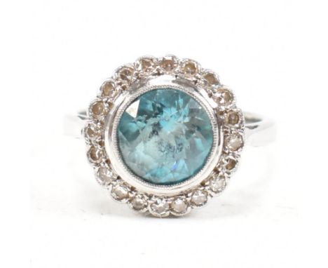 An 18ct white gold platinum and zircon and diamond cluster ring. The ring set with a central round cut blue zircon framed by 