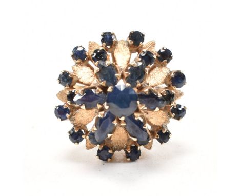 A 1970s 18ct yellow gold and sapphire bombe cocktail ring. The ring having a round cut sapphire to the centre surrounded in a