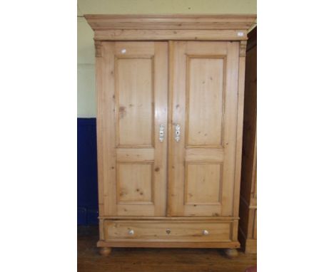 A Continental stripped pine two door wardrobe, with a drawer below, 130 cm wide