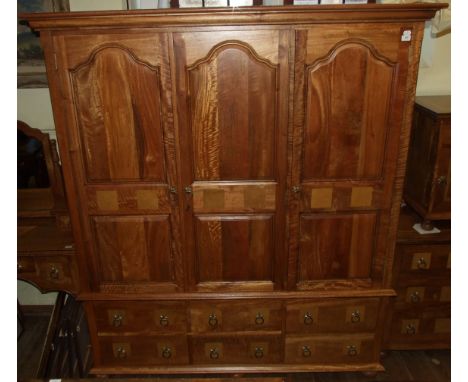 A matching wardrobe, having three panel doors above four short drawers and a small door, on bun feet, 174 cm wide