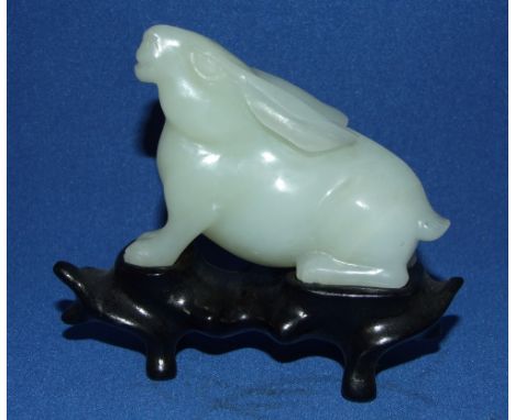 A carved jade rabbit, on a hardwood stand, 8.5 cm high