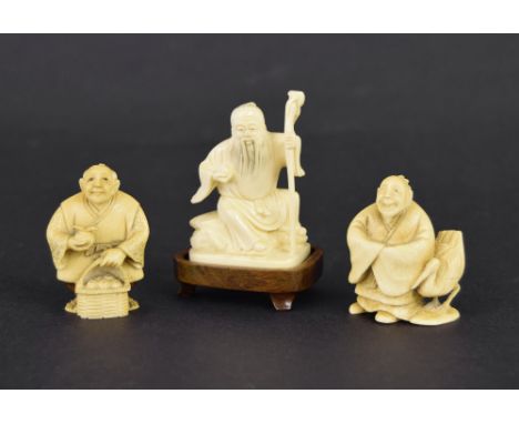Japanese ivory netsuke modelled as an elderly man holding a staff, upon a hardwood base, 2.5" high; together with two other n