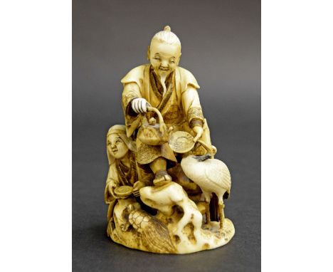 Japanese carved stained ivory okimono, modelled with two figures in a naturalistic setting holding bowls with a crane and tor