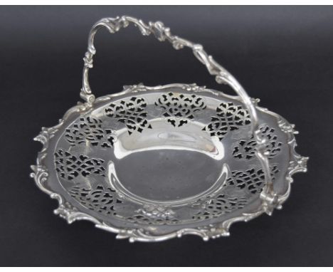 Attractive Victorian silver circular cake basket, with a cast foliate swing handle and similar border enclosing a pierced eng