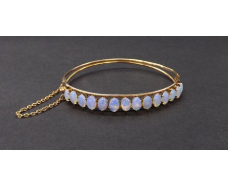 Antique gold diamond set hinged bangle set with fourteen opal cabochons, with safety chain, 9.6gm, 63mm wide