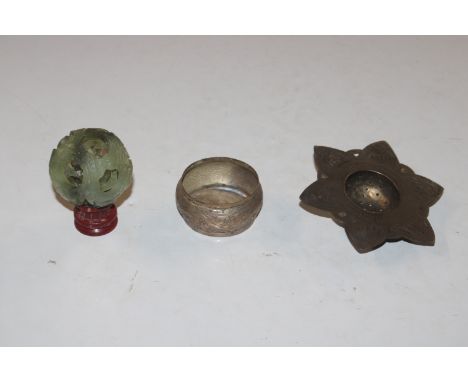 A jade coloured puzzle ball on wooden stand and an Eastern white metal strainer decorated with elephants 