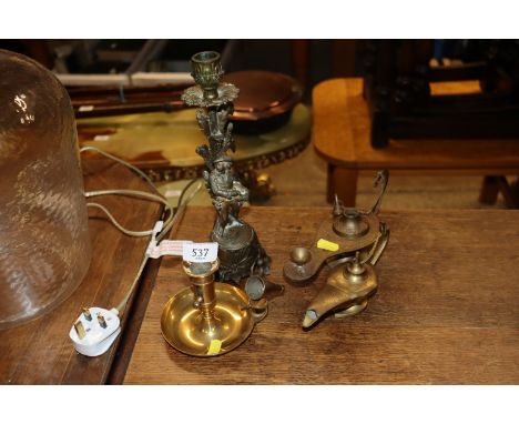 A brass chamber stick and snuffer; two brass Roman type lamps; and a gilded spelter candlestick with figural decoration 