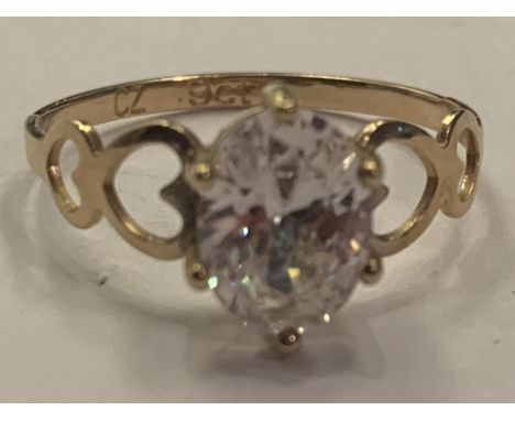 A 9 CARAT GOLD RING WITH A CLEAR STONE AND HEART DECORATION SHOULDERS SIZE L 